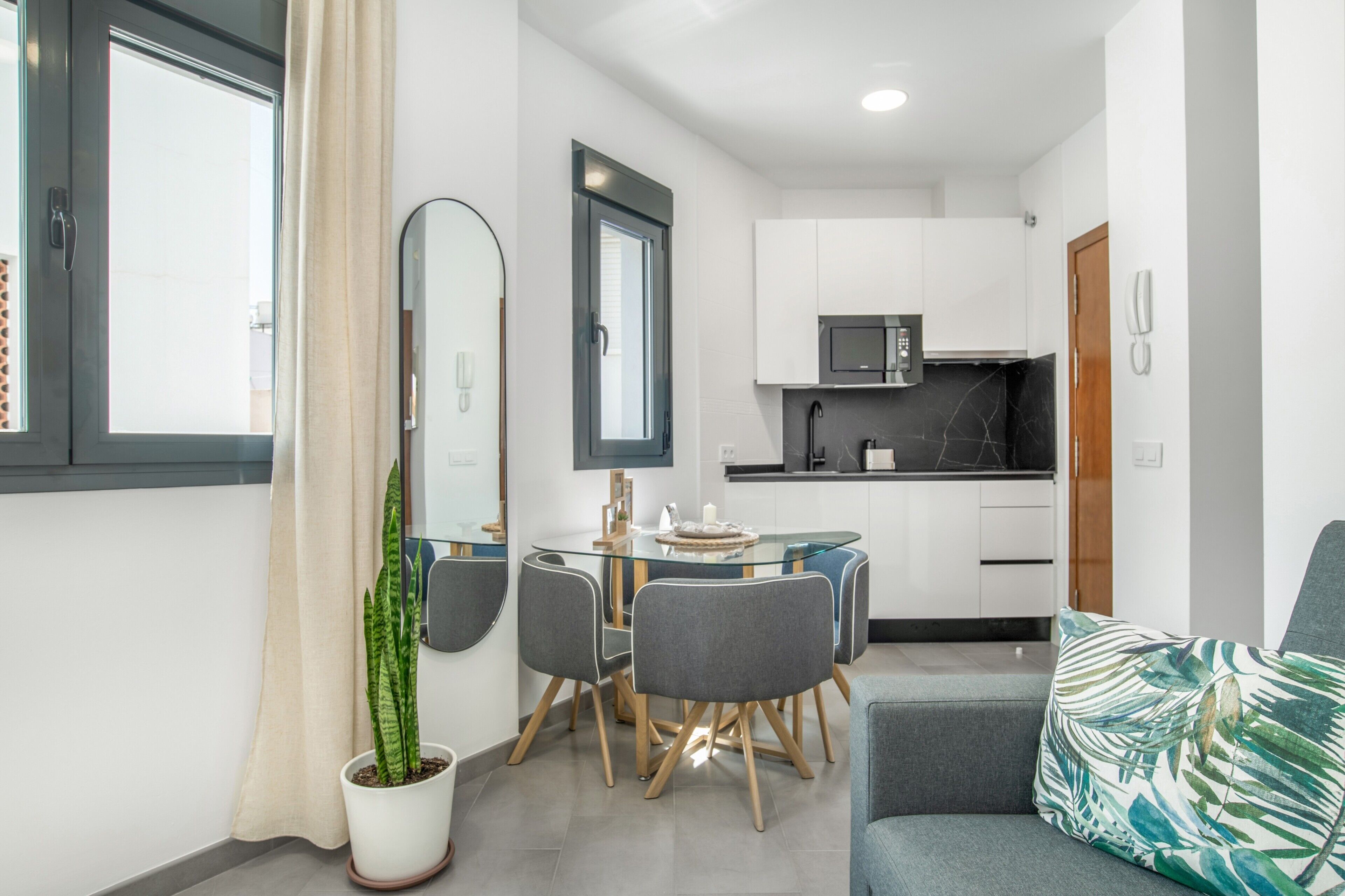 A compact living space with a dining area, kitchenette, and a sofa.