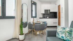 Ein kompakter Wohnbereich mit Essplatz, Küchenzeile und einer Couch.