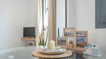 A glass table with a candle, seashells, and framed pictures.