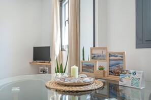 A glass table with a candle, seashells, and framed pictures.