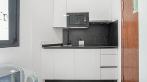 Eine moderne Küche mit weißen Schränken, einer schwarzen Arbeitsplatte, einer Mikrowelle und einem Spülbecken.