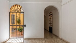 A hallway with a tiled floor, a metal gate with a sunburst design, and a potted plant. - Cozy Mezzanine Apartment by Wonderful Italy (Bologna)
