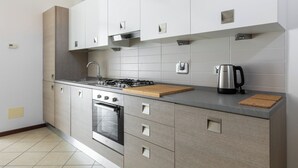 A modern kitchen with a gas stove, oven, and stainless steel appliances. - Cozy Mezzanine Apartment by Wonderful Italy (Bologna)