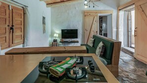 A rustic kitchen with a gas stove, wooden cabinets, and a television.
