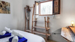 Una habitación con una cama, una escalera de madera, una ventana y un escritorio con una lámpara.
