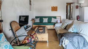 Una sala de estar acogedora con un sofá verde, una mesa de centro de madera, un sofá negro y un sillón estampado.