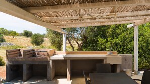 Um pátio externo com churrasqueira, área de estar e mesa.