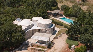 Uma villa com piscina, estruturas de pedra e área de estar coberta ao ar livre.