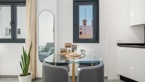 Eine moderne Küche mit weißen Schränken, einem Glastisch und einem Blumentopf.
