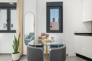 Una cocina moderna con armarios blancos, una mesa de comedor de vidrio y una planta en maceta.