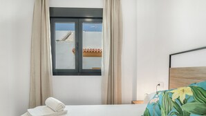 Ein Hotelzimmer mit Bett, einem Vorhangfenster, Blick auf ein Gebäude und einem Holzkopfteil.