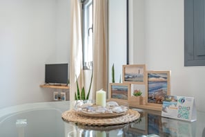 A glass table with a candle, seashells, and framed pictures.