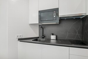 Una cocina moderna con microondas integrado, un lavabo y una cafetera.