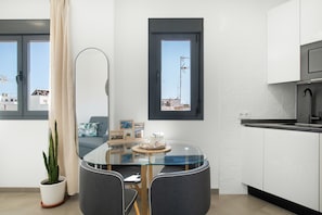 Una cocina moderna con armarios blancos, una mesa de comedor de vidrio y una planta en maceta.