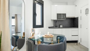 A modern kitchen with white cabinets, a microwave, and a glass dining table with chairs. - Apartment 'Cervantes Homes No3' with Shared Terrace, Wi-Fi and Air Conditioning (Conil de la Frontera)