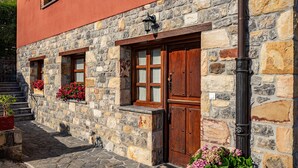 Ein Steinhaus mit Holztüren und -fenstern, einer Treppe und Blumenkästen.