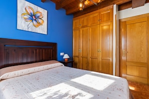 Un dormitorio con una cama, un armario de madera y un cuadro en la pared.