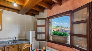 Eine Küche mit Fensterblick, Holzschränken, einem Spülbecken und einem Frühstücksbrett auf einem Tisch.
