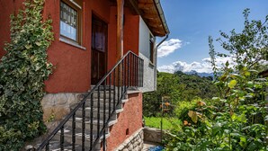 Ein rotes Gebäude mit rustikalem Steinunterbau, einem hölzernen Balkon und einer Treppe zum Eingang.