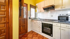 Eine Küche mit Holzausstattung, einer Mikrowelle, einem Backofen und einem gefliesten Boden.