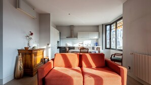 A modern living room with a sofa, a wooden cabinet, and a dining area in the background. - Apartment 'Annecy - Le 10' with Balcony, Wi-Fi and Air Conditioning (Annecy)
