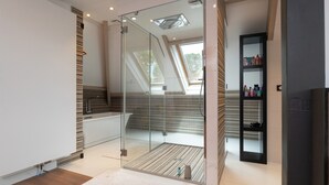 Un bagno moderno con cabina doccia in vetro, parete rivestita in listelli di legno e un lucernario.