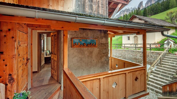 Un bâtiment en bois doté d’un balcon, d’un escalier et offrant une vue sur la montagne.
