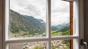 Une vue par la fenêtre sur un paysage montagneux, avec un village en contrebas.