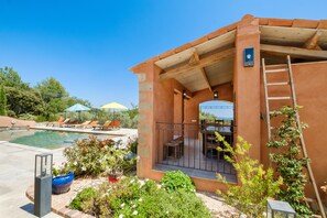 Un espace aménagé au bord de la piscine, avec une terrasse, une pergola en bois et une vue sur la piscine.