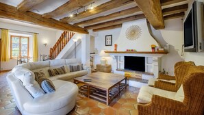 A living room with a white sofa, wicker chairs, a fireplace, and a wooden ceiling. - Villa 'Propriété Fontaine Margo': Peaceful Retreat with Mountain Views (Seillans)