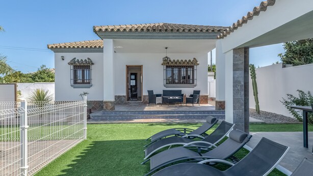 A house with a patio, outdoor seating, and a fenced yard.