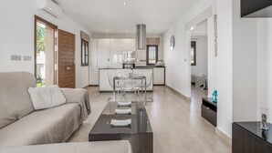 A modern living room with a sofa, a coffee table, and a kitchen in the background.