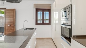 A modern kitchen with a stainless steel range hood, a built-in oven, and a window with a view.