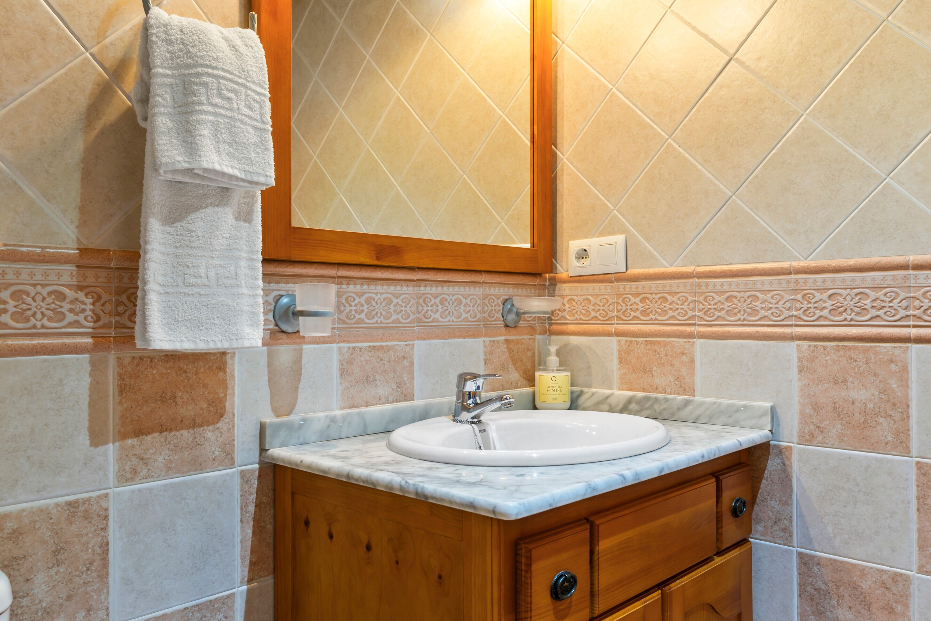 Un bagno con lavandino, specchio, porta asciugamani e piastrelle decorative.