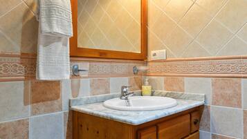 Un bagno con lavandino, specchio, porta asciugamani e piastrelle decorative.