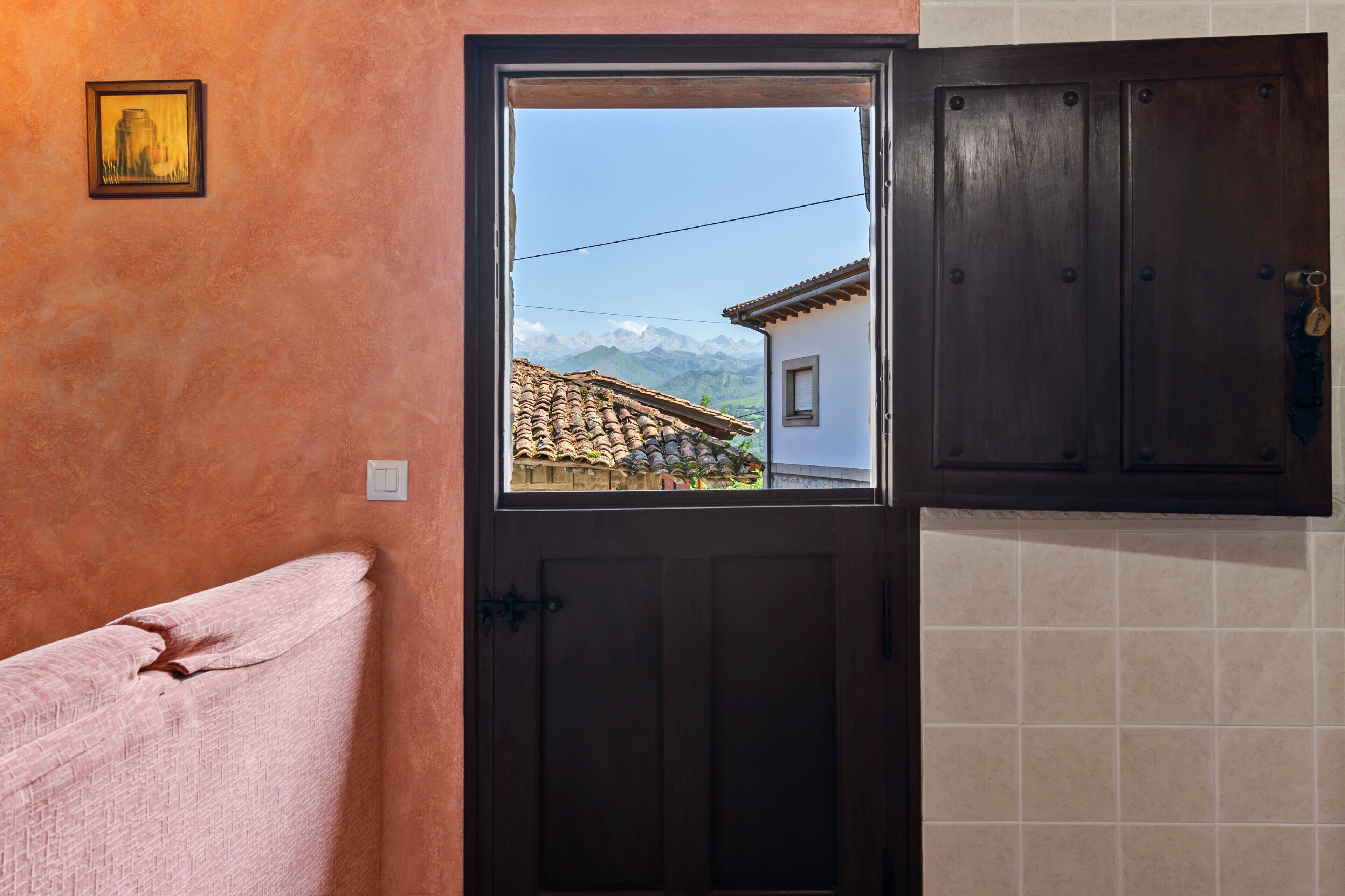 Ein Zimmer mit Holztür, einem Fenster mit Bergblick und einem Handtuch auf dem Boden.