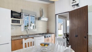 Une cuisine moderne équipée d’un four à micro-ondes, d’une cuisinière et d’un lave-vaisselle. On y trouve une table à manger avec un saladier rempli de fruits.