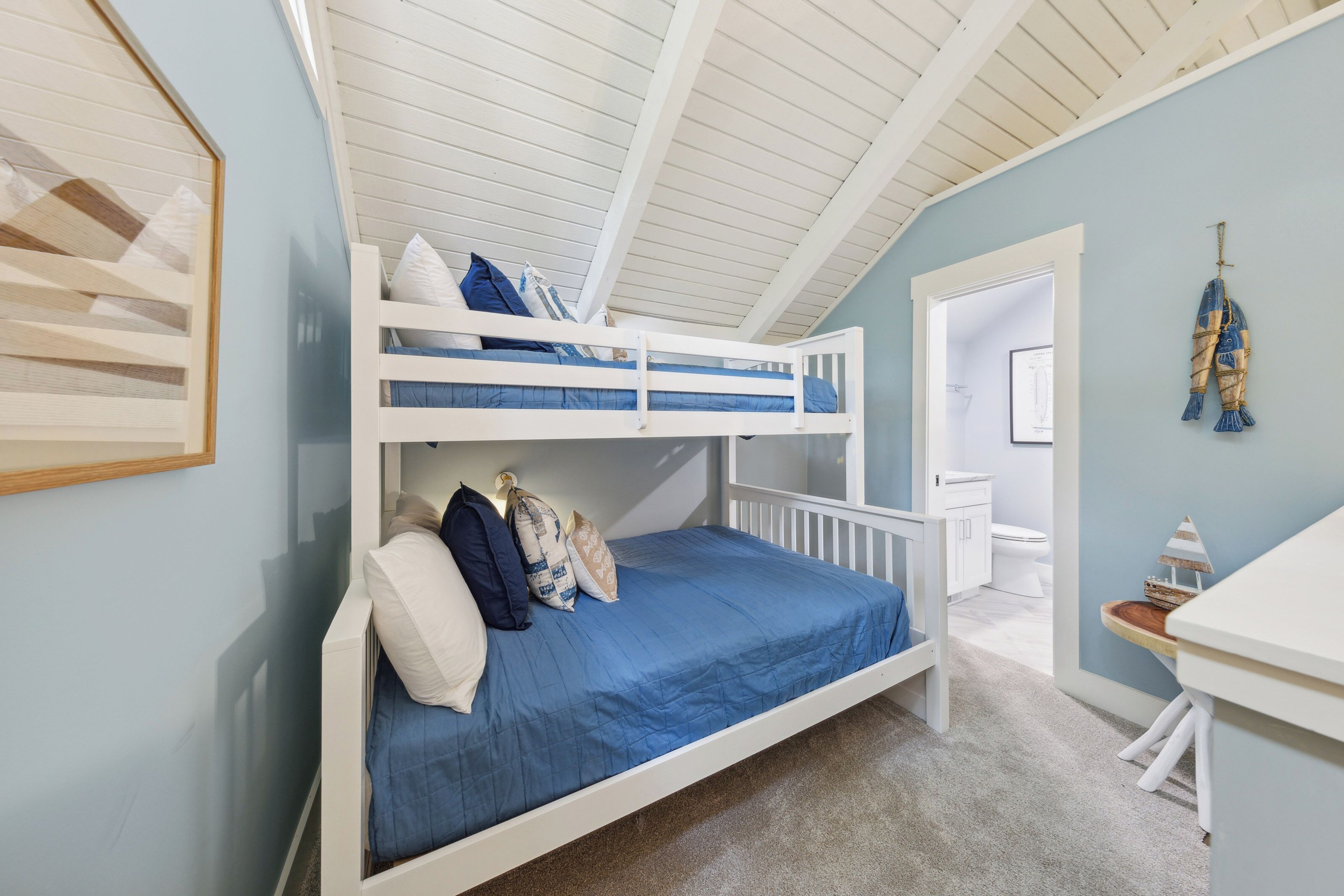 Une chambre avec un lit superposé, un plafond blanc et des murs bleu clair. On y trouve un radiateur blanc sous le lit et une petite table en bois avec une lampe à côté du lit.