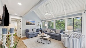 Una sala moderna con un sofá modular, una mesa de centro redonda y un sillón a rayas.