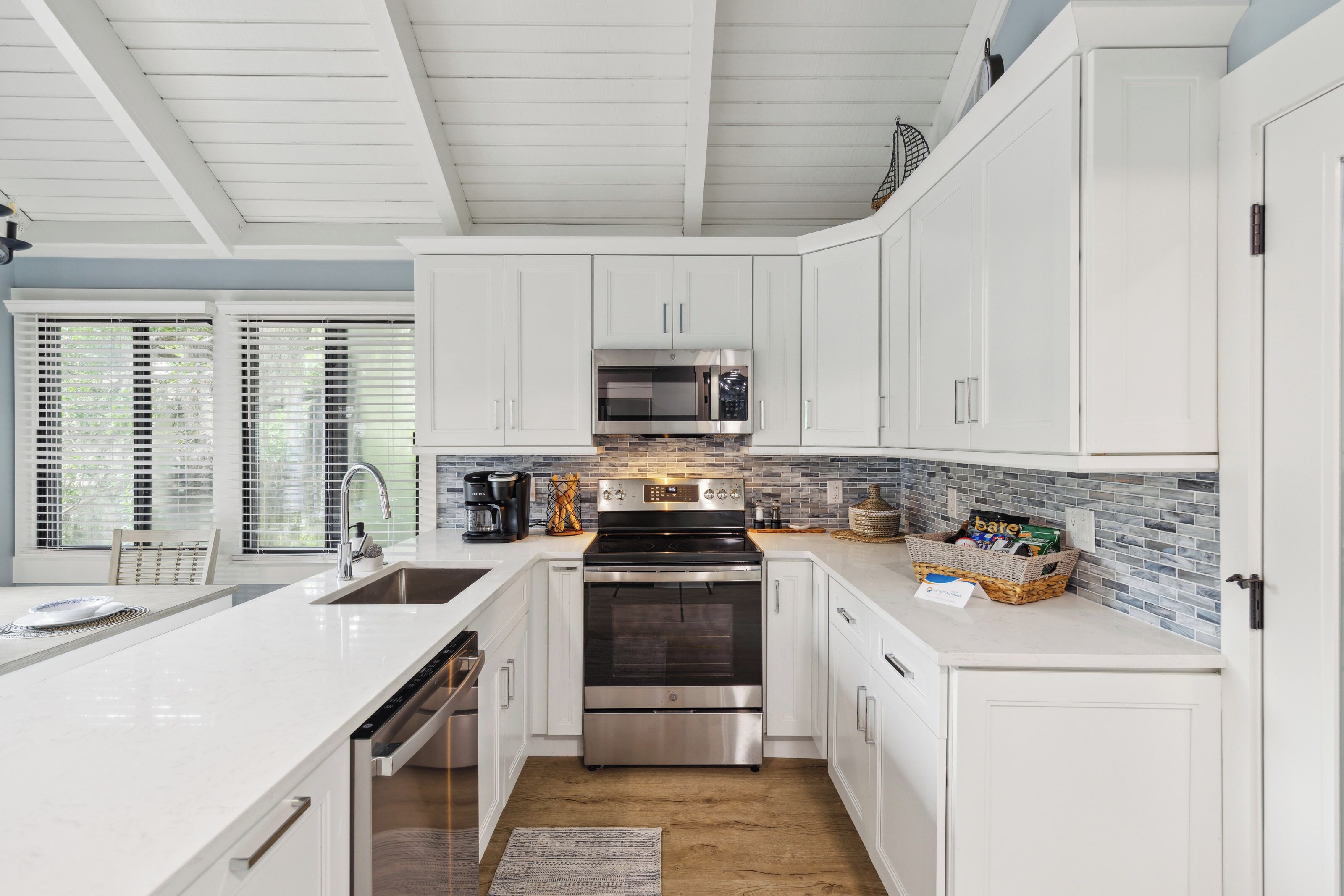 A modern kitchen with white cabinetry, stainless steel appliances, and a tiled backsplash.