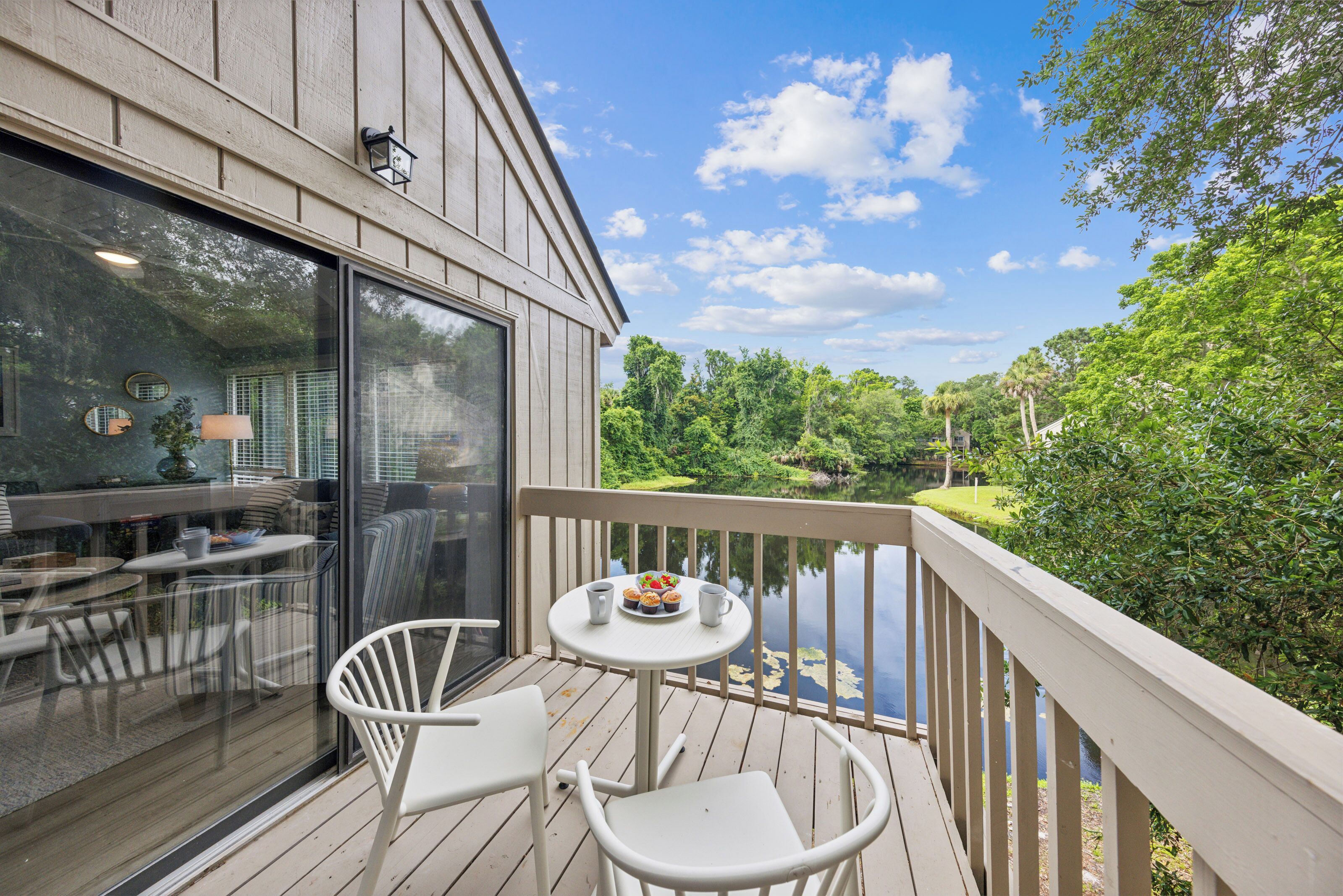 Ein Balkon mit Tisch und Stühlen mit Blick auf einen See und viel Grün.