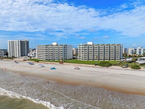 Ett hotell vid stranden med flera höga byggnader, en sandstrand och en klar himmel.