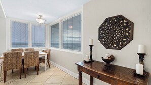 Ein Essbereich mit Tisch und Stühlen, einer Wanddekoration und einem Fenster mit Jalousien.