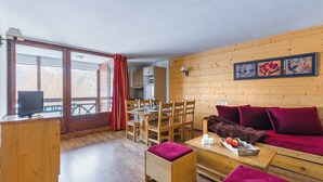 Ein gemütliches Cabin-Interieur mit einem Holzespeisetisch, Stühlen, einer Couch und einem Fernseher auf einer Holzkommode.