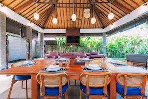 Enjoy meals in a spacious dining area with a large table, sofa set, and comfortable seating.