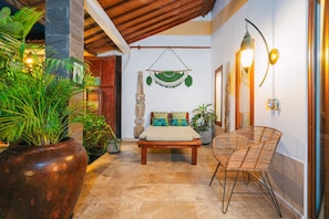 Cozy retreat with a wooden bed, wicker chair, and lush greenery.