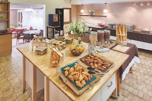 A buffet setup with various food items, including bread and pastries, in a hotel setting.