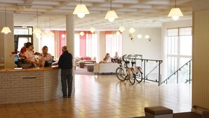 Een ruime lobby met een receptiebalie, een zithoek en fietsen.