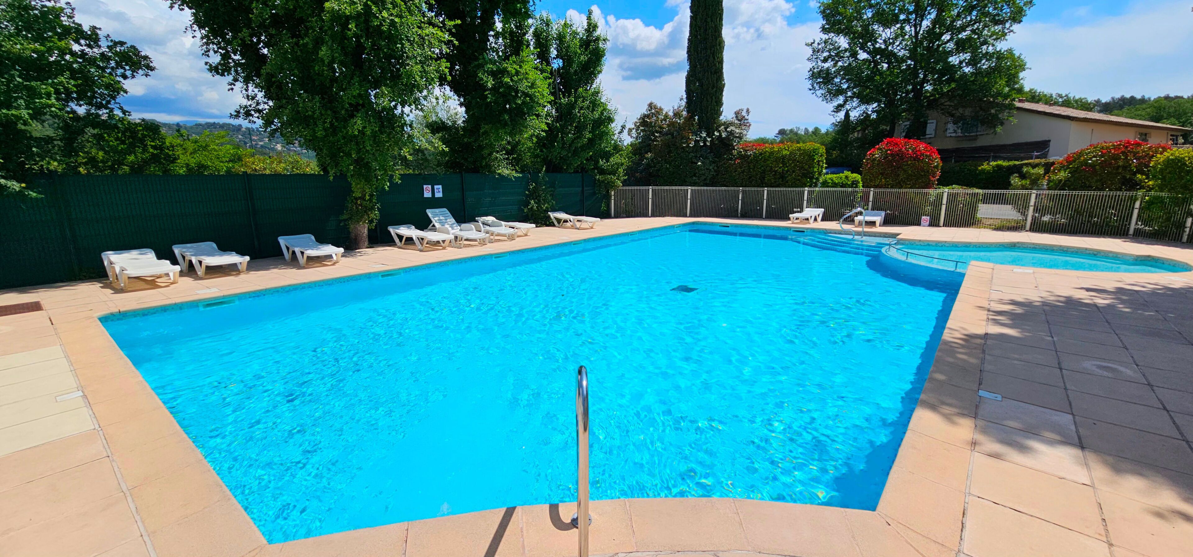 Une piscine rectangulaire à l’eau d’un bleu limpide, entourée d’une terrasse carrelée.