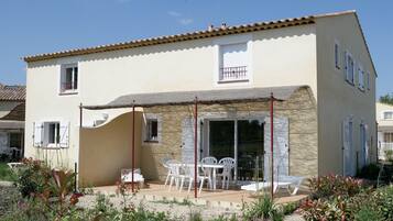 Un bâtiment à deux étages doté d’un patio aménagé avec du mobilier d’extérieur.